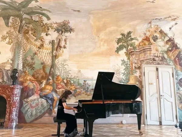 A pianist at a grand piano in the frescoed hall of Schloss Laudon.